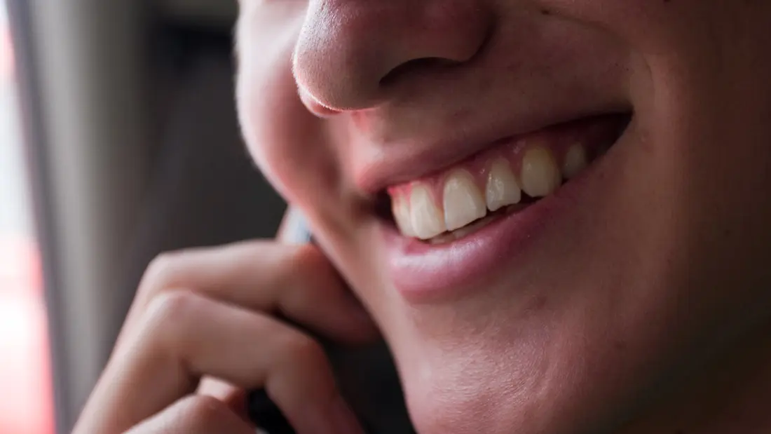 Person smiling while using a smartphone to share a message
